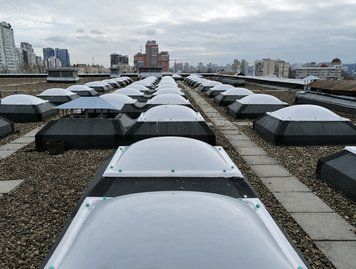Група купольних зенітних ліхтарів із полікарбонату на білій покрівлі, вигляд зверху